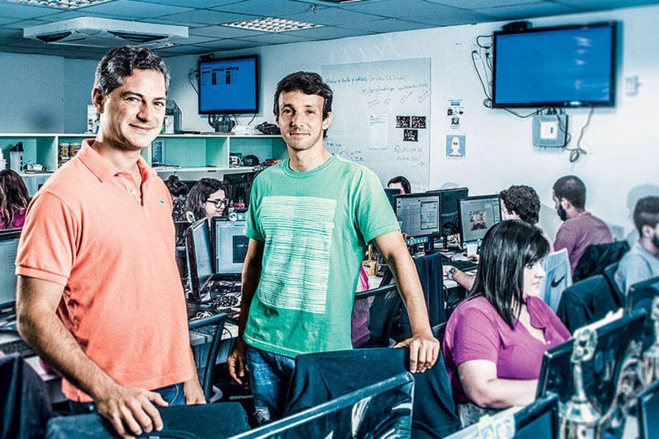 Alex Tabor and Julio Vasconcellos standing among desks in the Peixe Urbano office