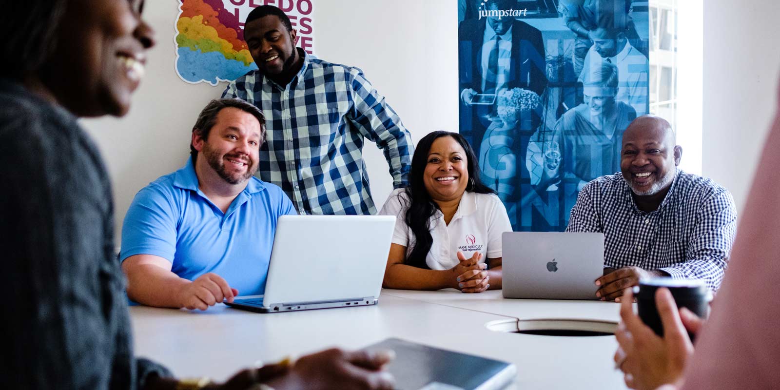 Entrepreneurs smiling around a table during a JumpStart working session