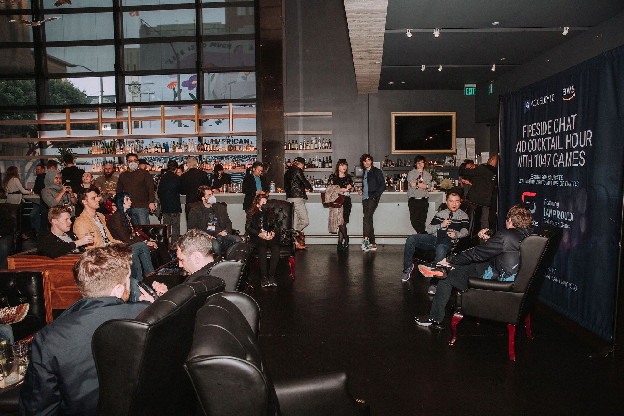 Junaili Lie holding a microphone opposite Ian Proulx at AccelByte’s 2022 fireside chat, surrounded by attendees