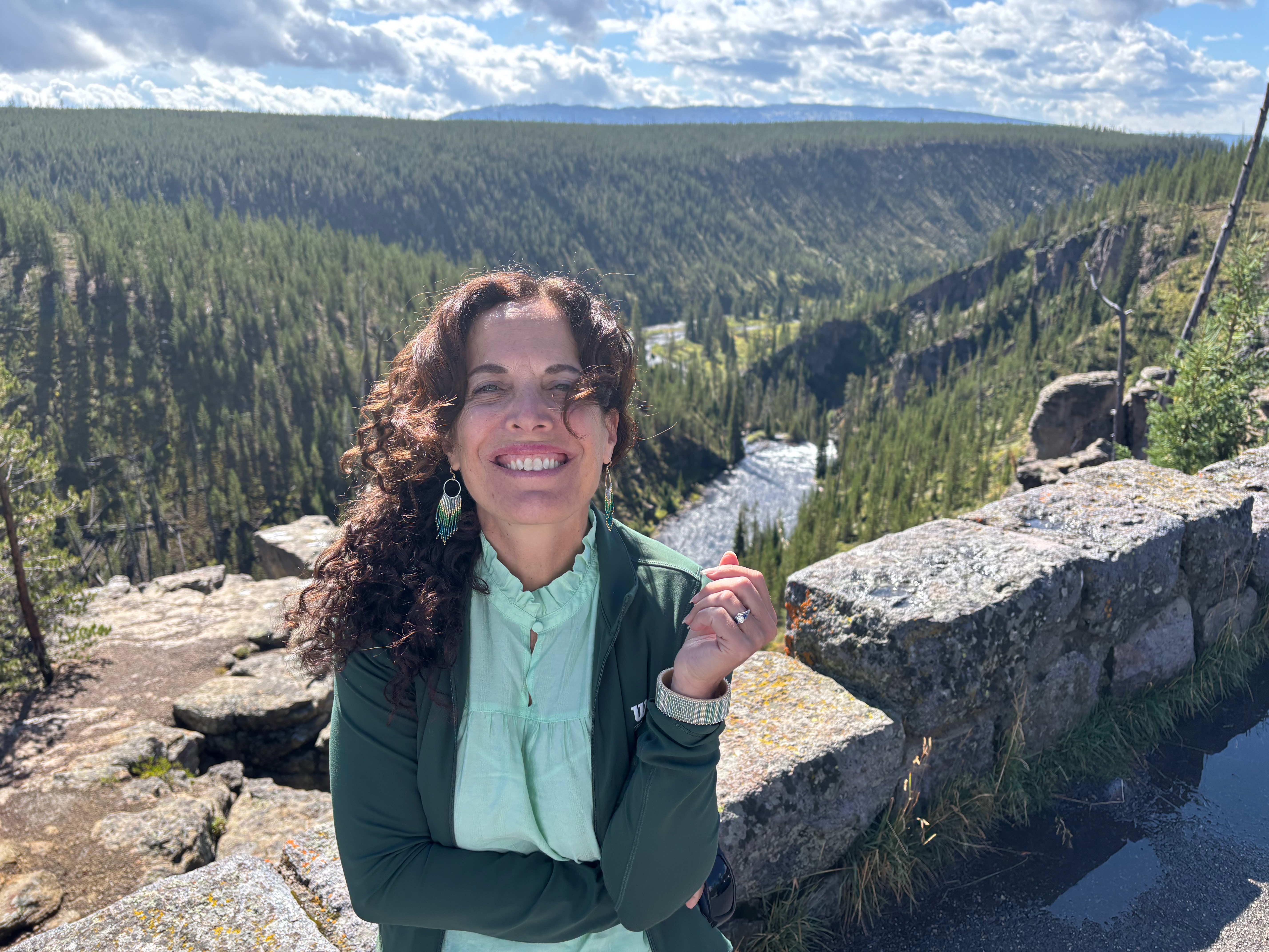 June Cohen outdoors beside a forested canyon and river
