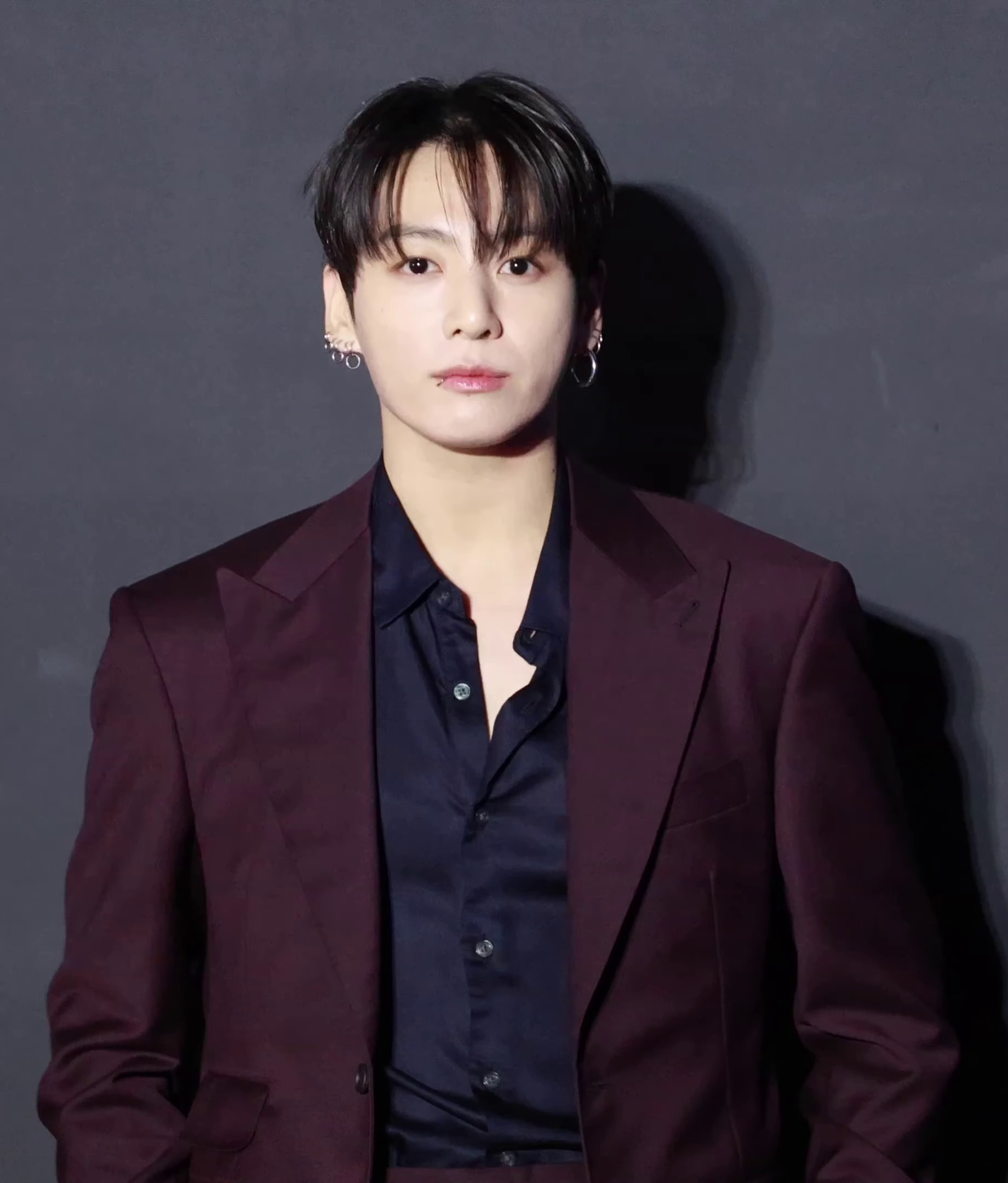 Jungkook in a burgundy suit at a Seoul photo call in February 2026