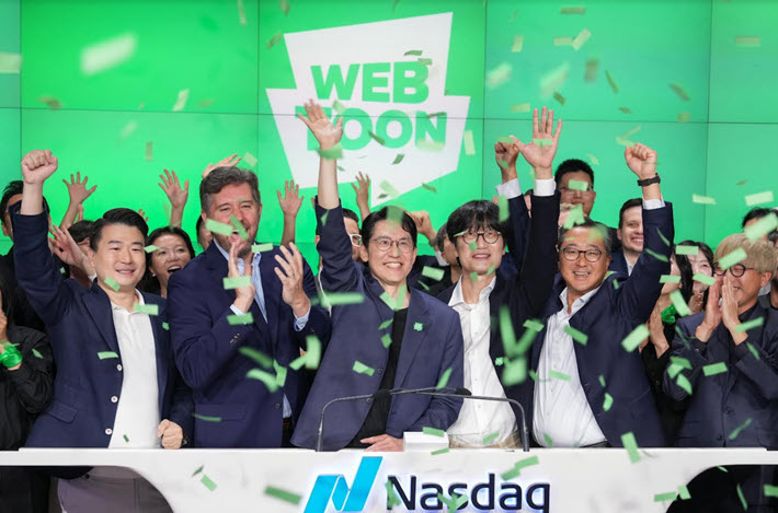 Junkoo Kim and WEBTOON colleagues celebrate the company’s Nasdaq debut beneath green confetti