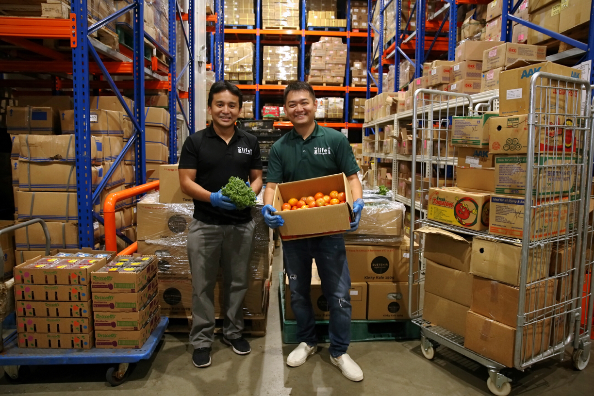 Joe Chen, left, and Justin Chou, right, holding vegetables in a Glife warehouse