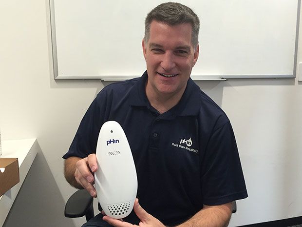 Justin Miller holding the white pHin pool monitor