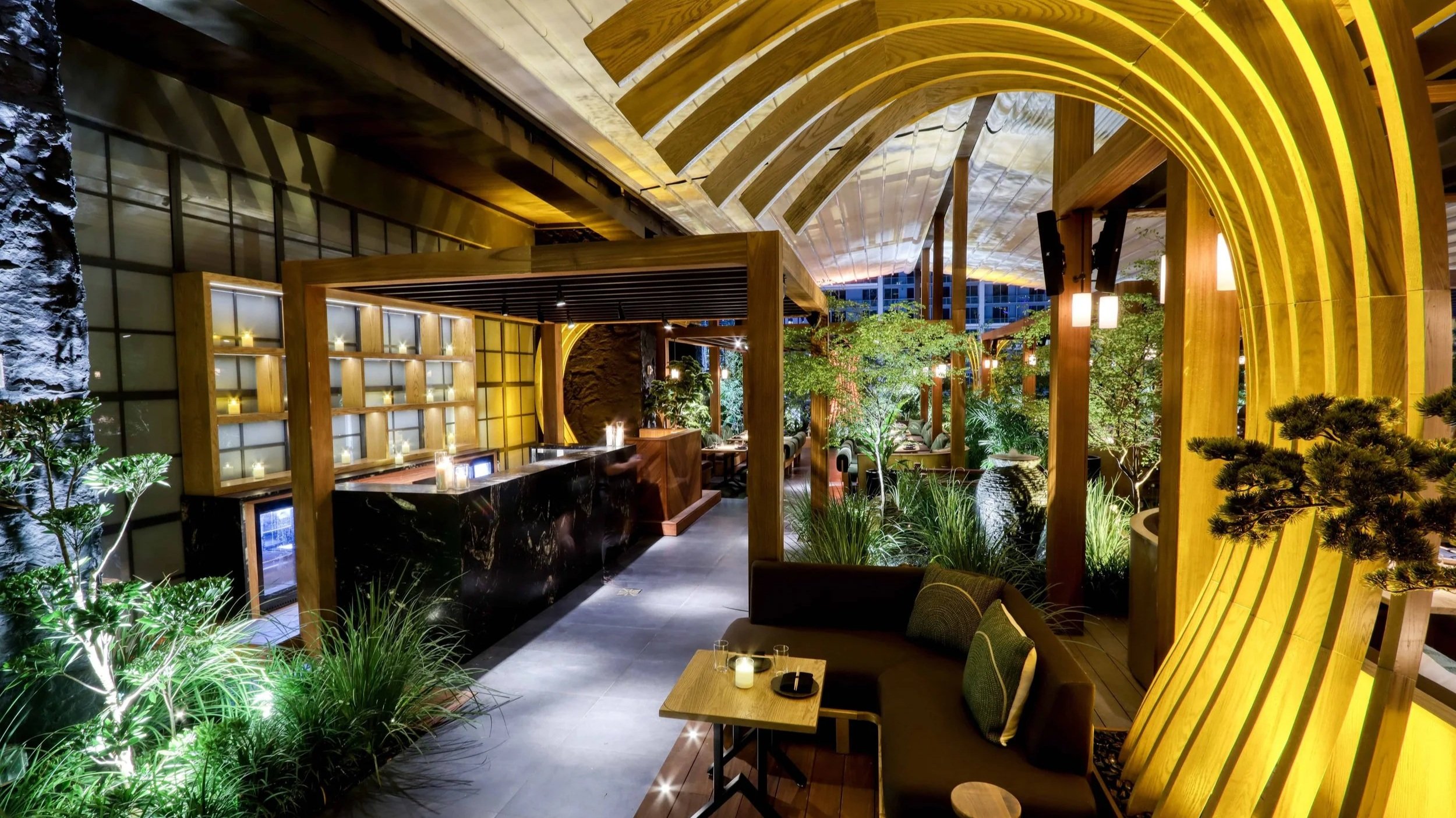 Warmly lit interior of Yamashiro Miami with slim black K-array speakers mounted among architectural timber arches