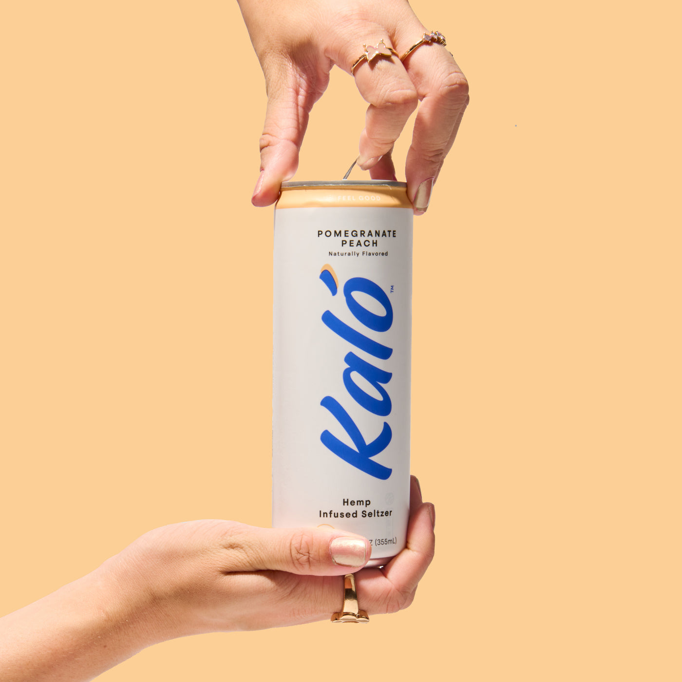 Hands opening an original Kaló Pomegranate Peach hemp-infused seltzer can