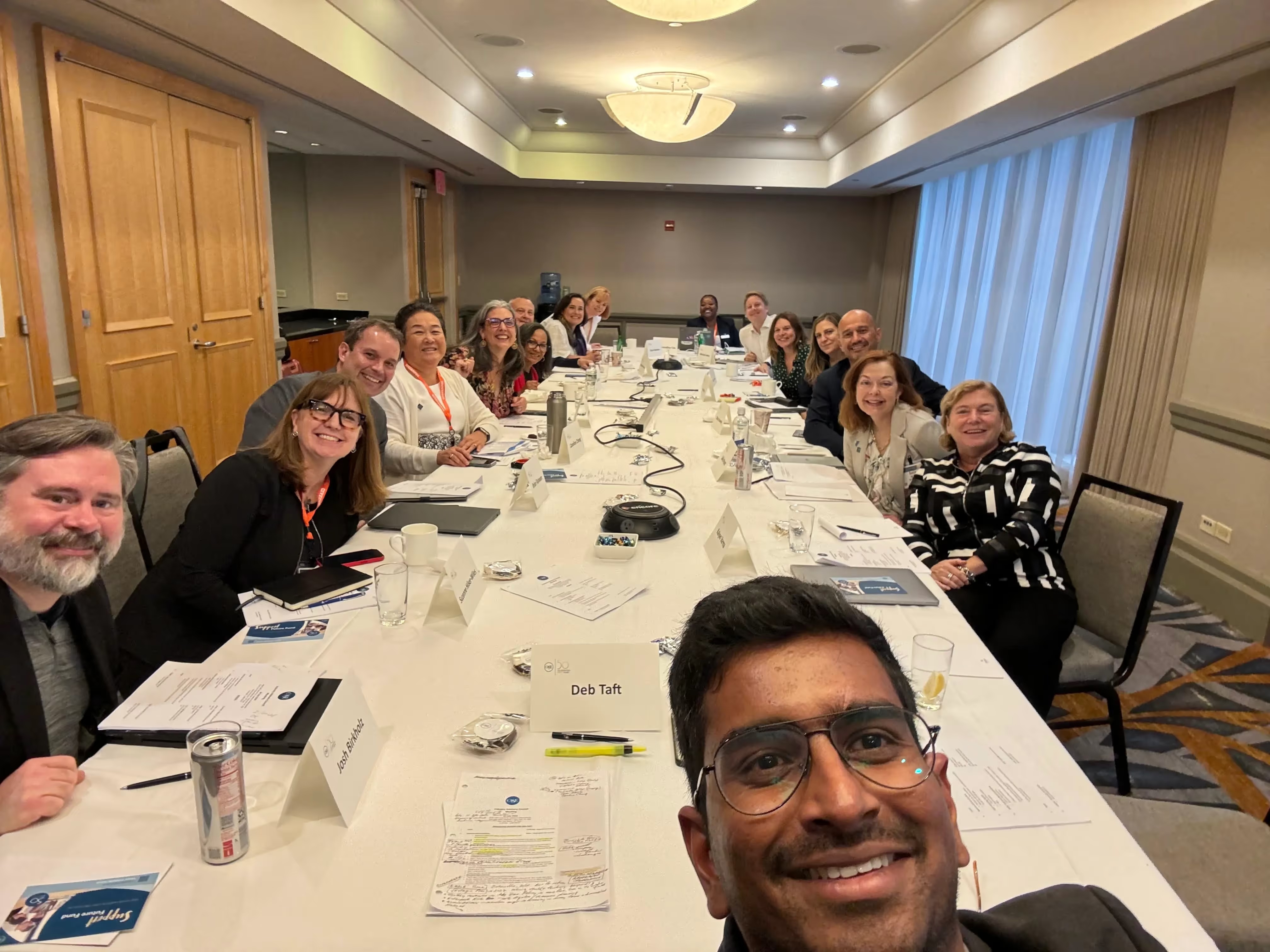 Kalyan Varma takes a group selfie with participants seated around a long meeting table