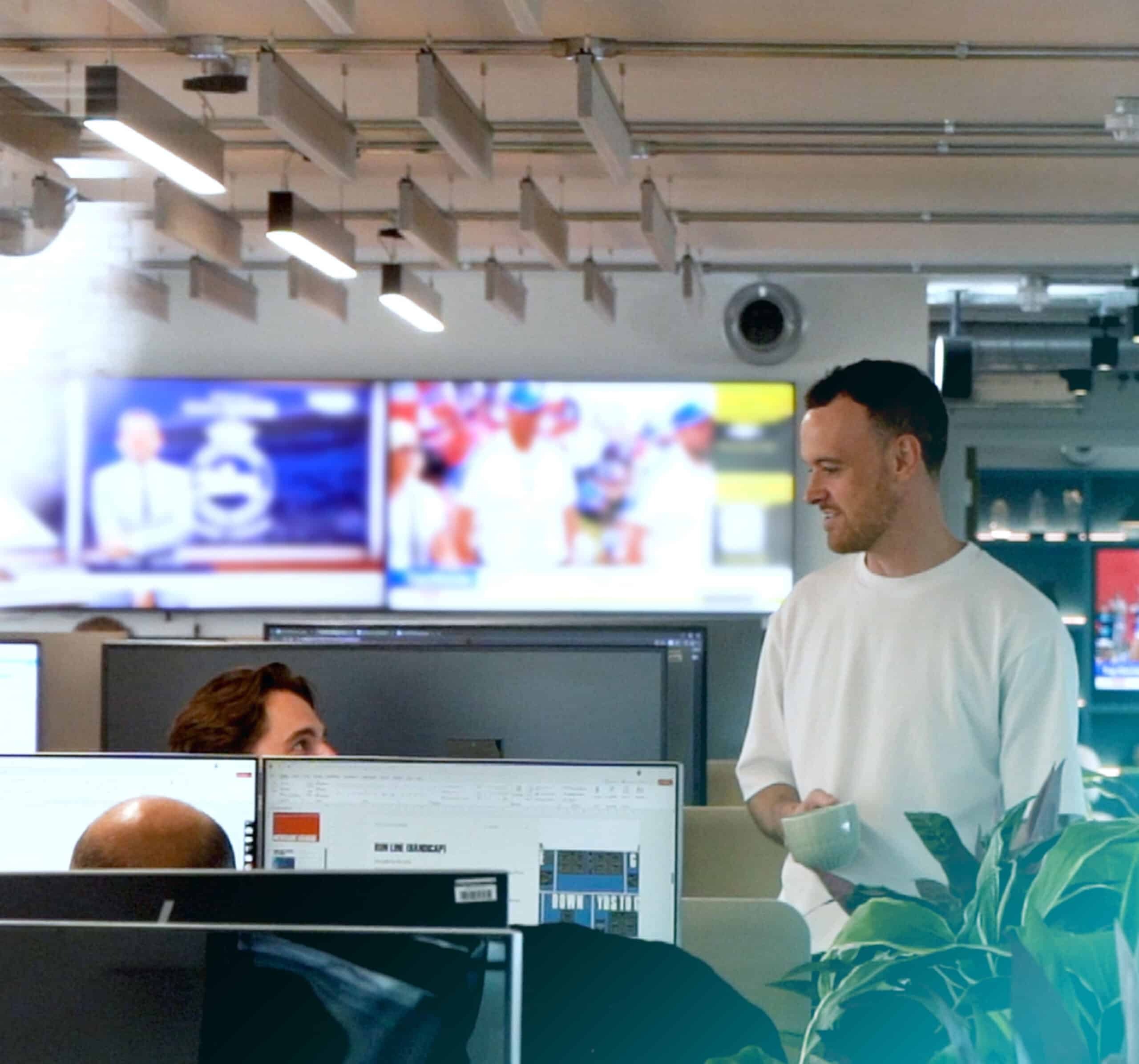 Kambi colleagues talking beside office monitors and sports screens