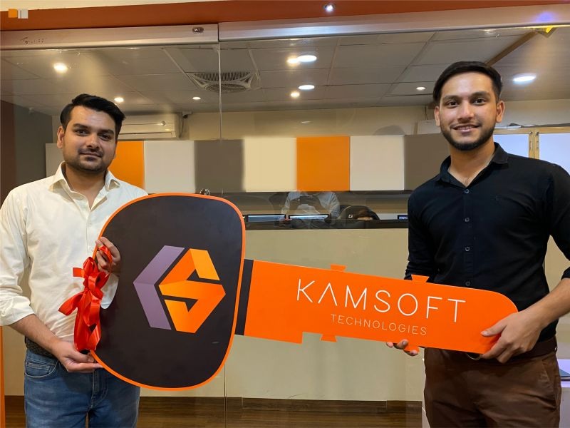 Two Kamsoft Technologies team members holding an oversized branded key in the Karachi office