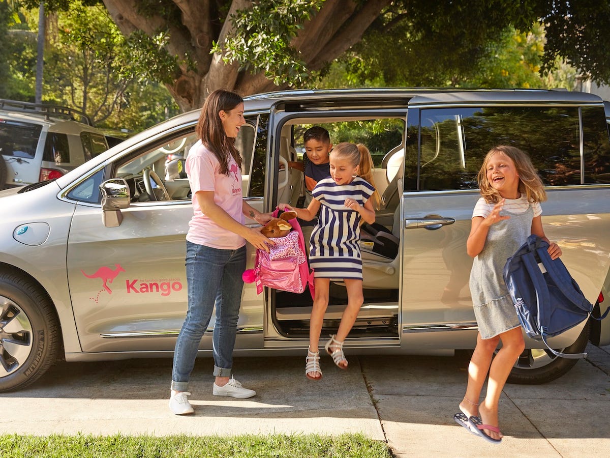 A Kango caregiver helps children leave a branded minivan