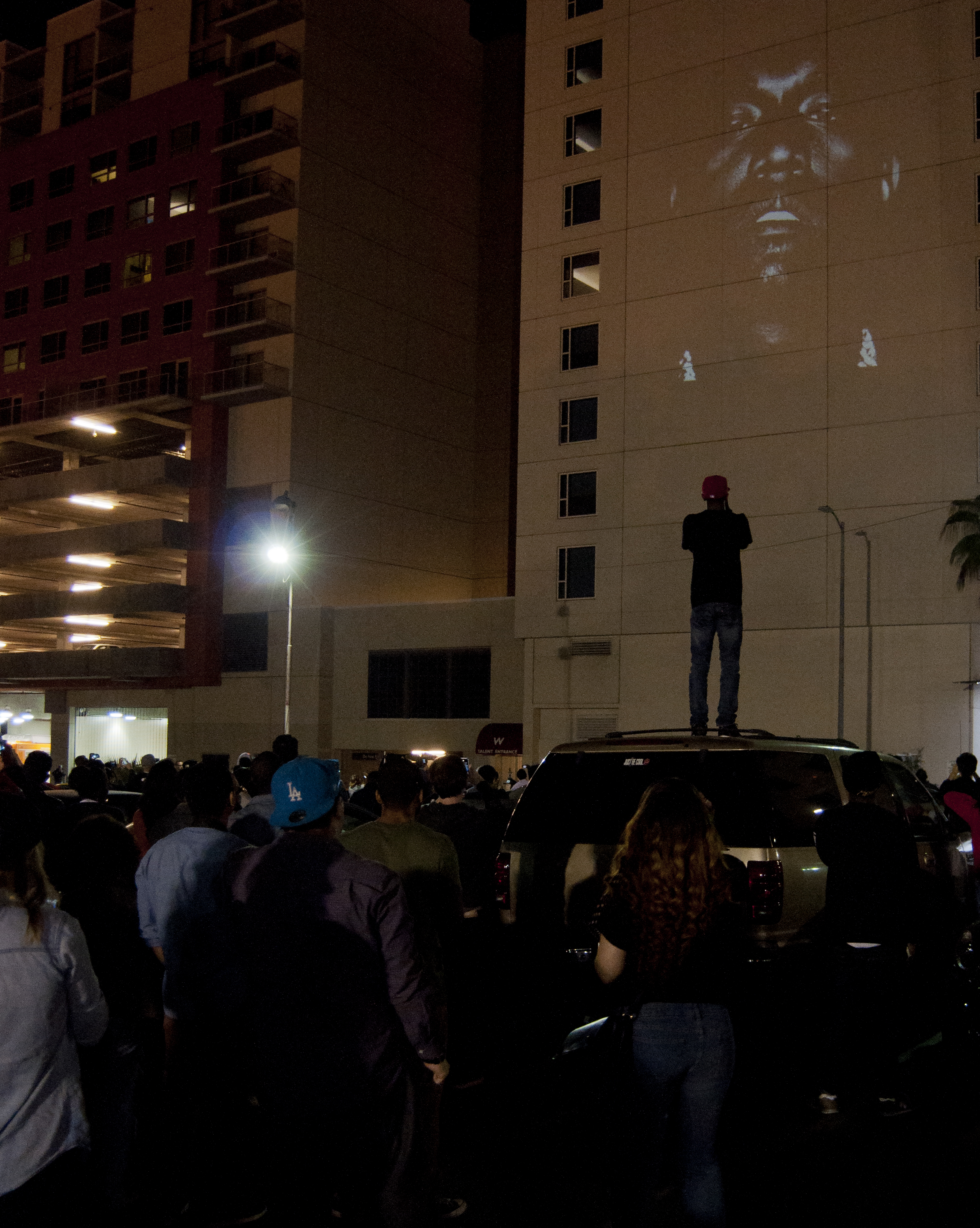 A crowd watches the black-and-white New Slaves projection on a building in Los Angeles in 2013