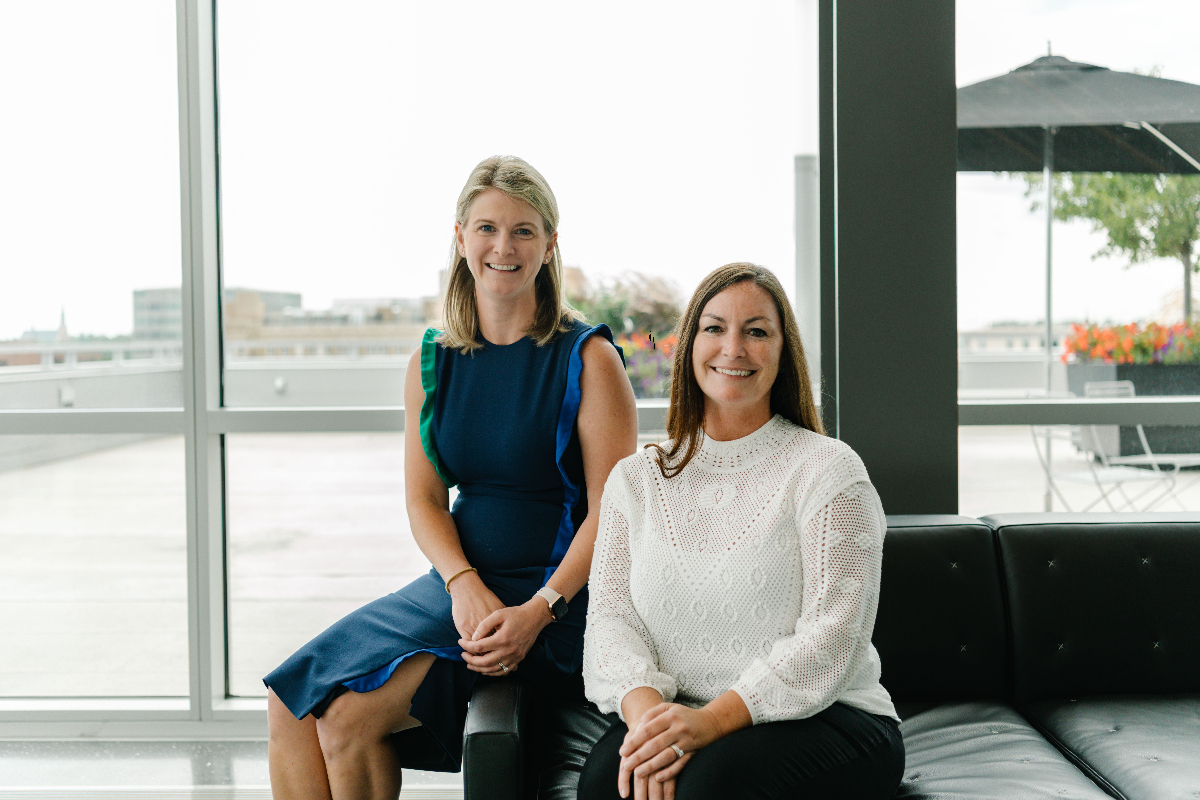 Asher co-owners Megan Bennett, left, and Kara Kelley, right, seated together beside large windows