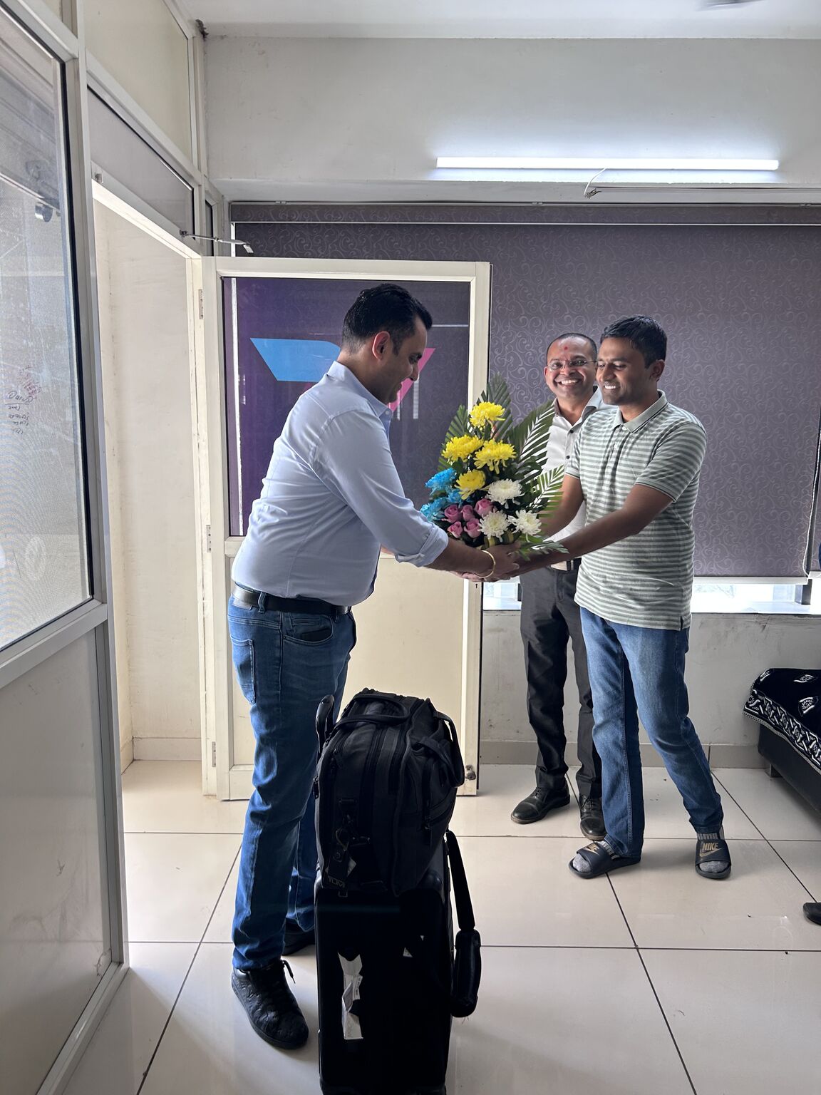 Karan Bakshi, left, receives a floral welcome during a visit to Vision Group's Ahmedabad office