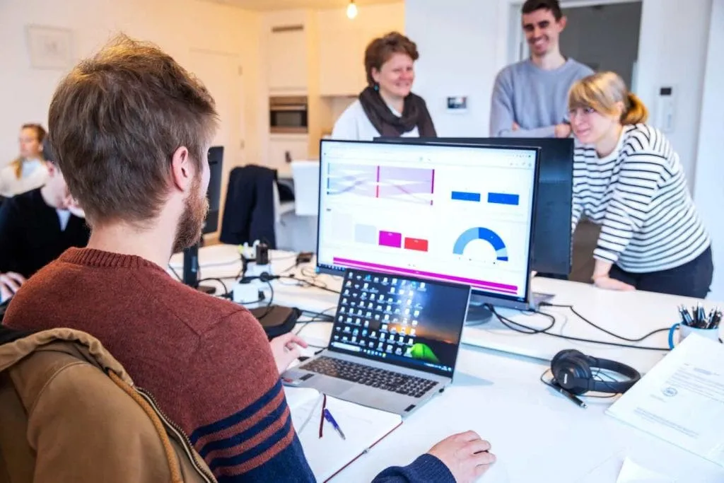 Cumul.io colleagues working together at a table with an analytics display behind them
