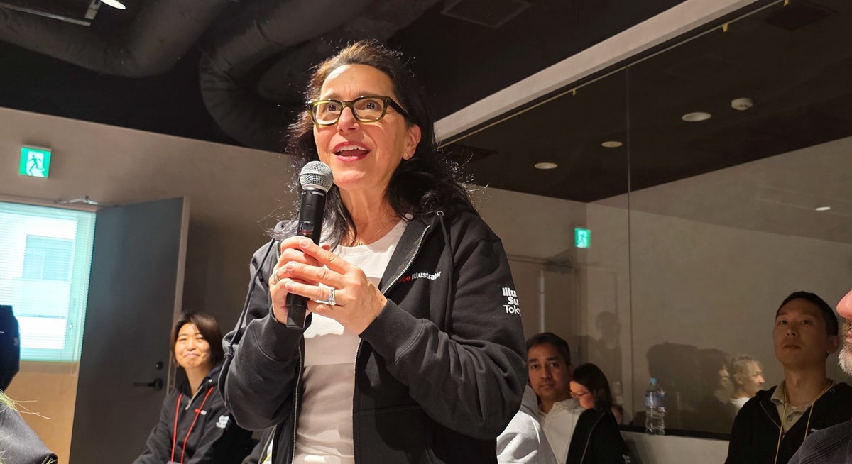 Karen Brewer speaks with a handheld microphone at the Adobe Illustrator Summit in Tokyo in February 2025