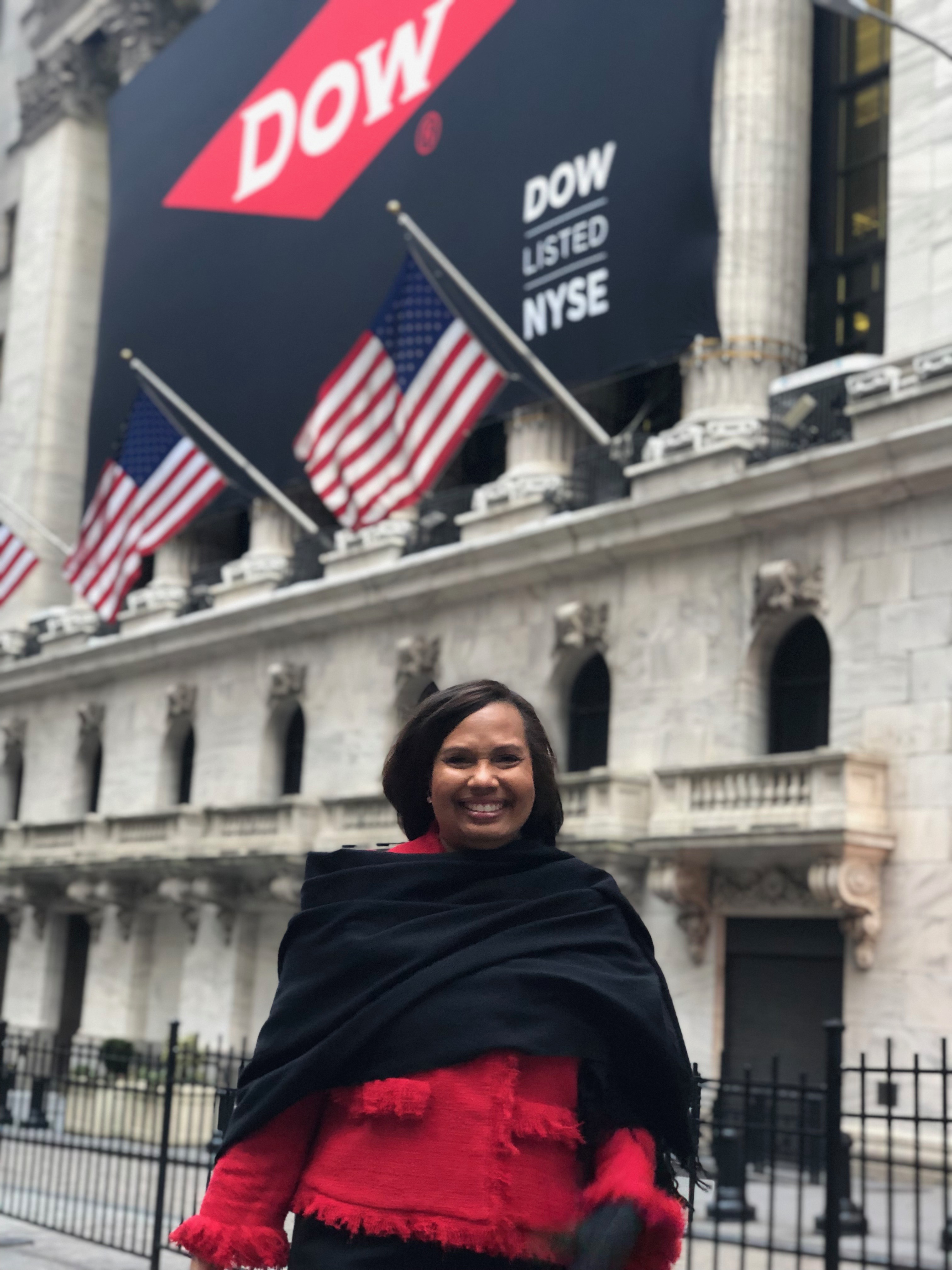 Karen S. Carter outside the New York Stock Exchange beneath Dow signage