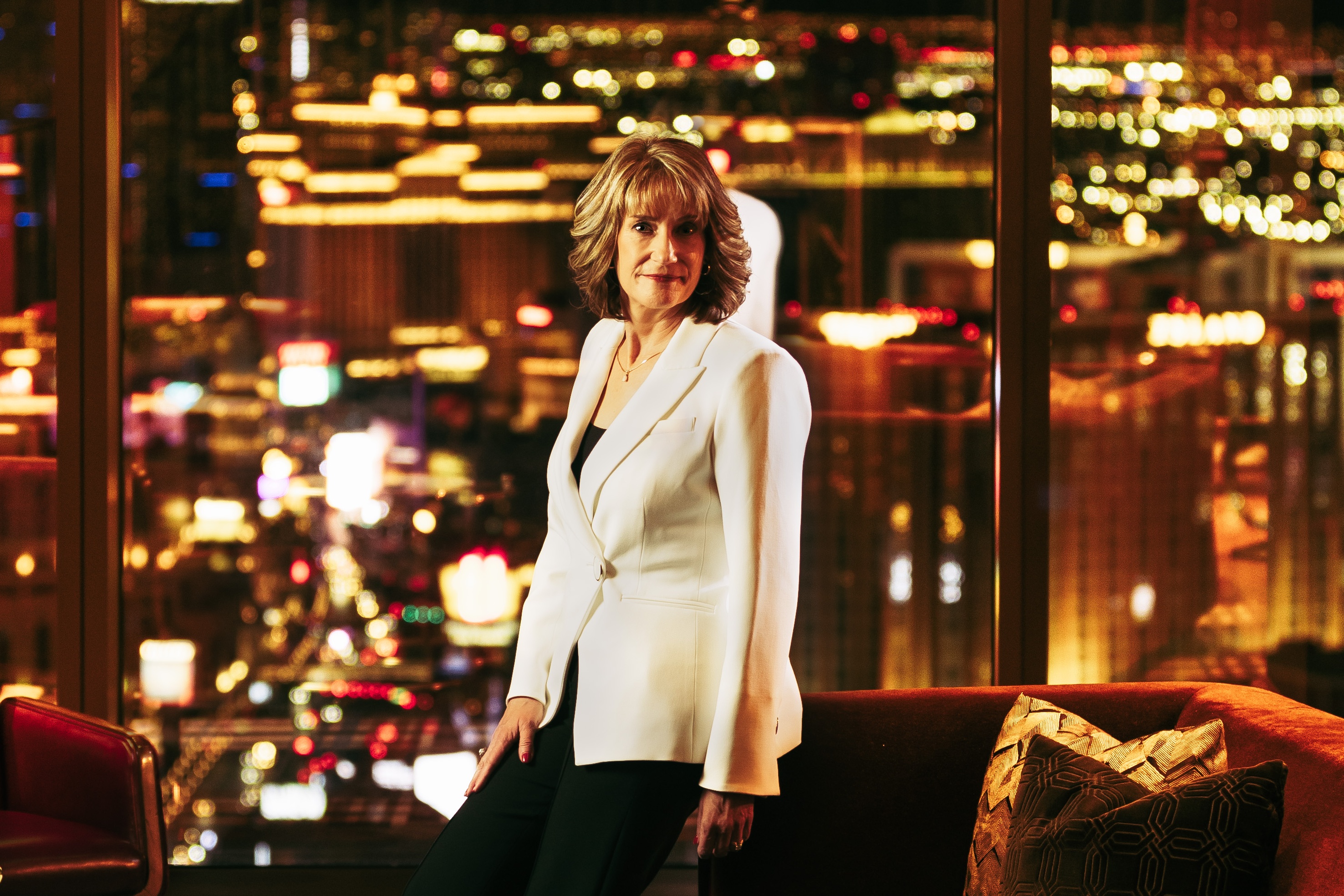 Karen Haller in a white blazer, photographed against a warmly lit Las Vegas interior