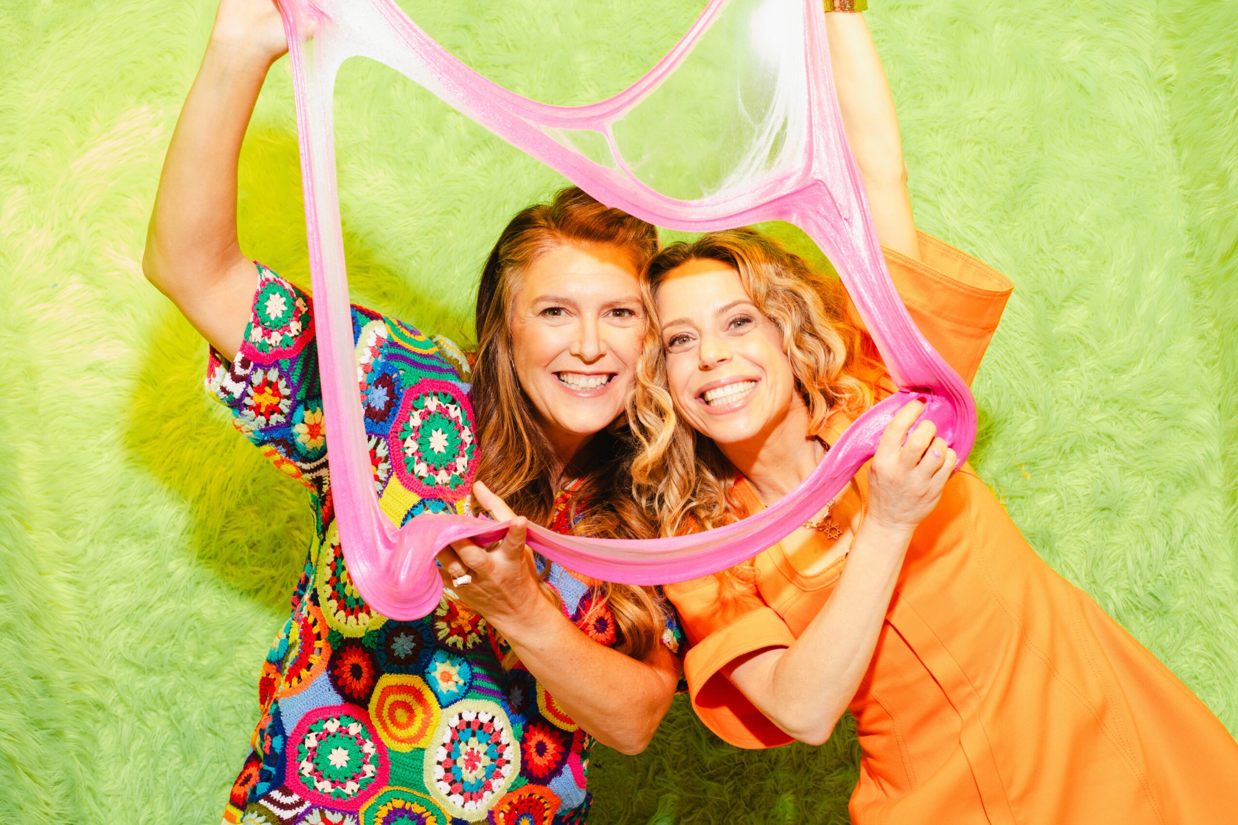 Sara Schiller, left, and Karen Robinovitz stretching a ribbon of pink slime