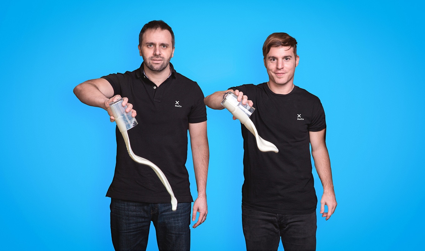 Karim Pichara and Matías Muchnick pour a NotCo milk product from clear cups against a blue background