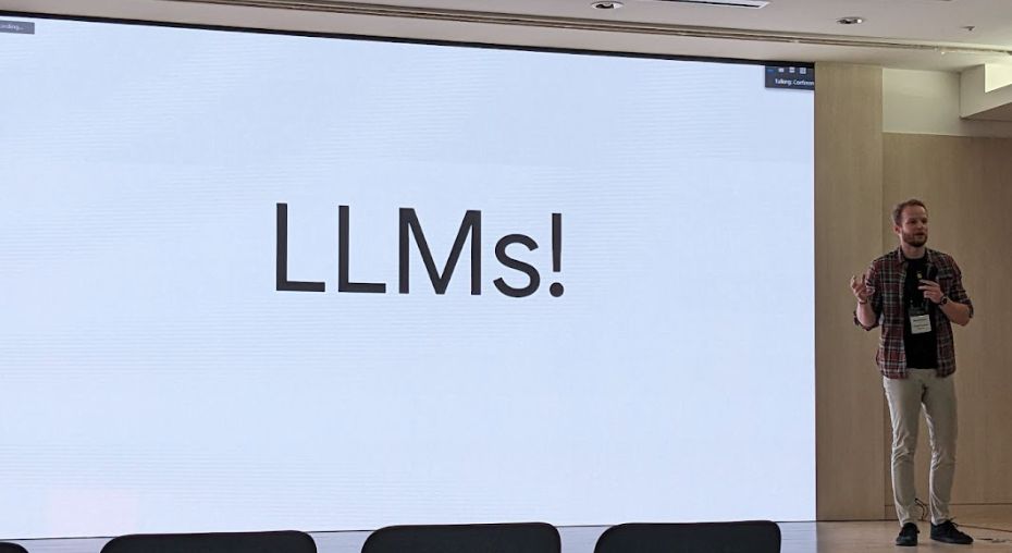 Karol Hausman speaking beside a slide marked LLMs at an Articulate Robots workshop