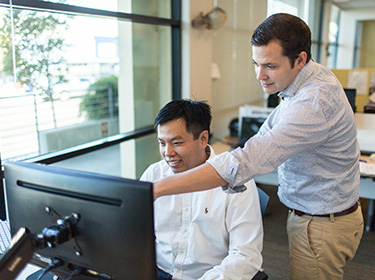 Alvin Tamsir seated at a computer as Karsten Temme points to the screen