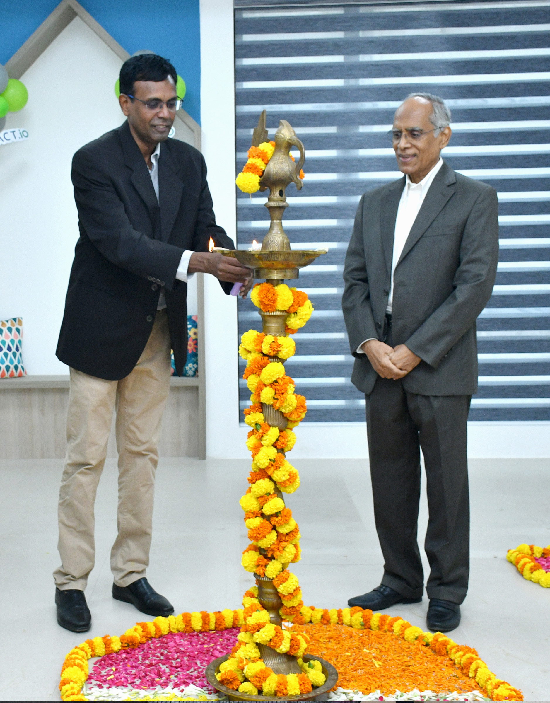 Karthik Karunakaran lighting a decorated ceremonial lamp beside Lakshmi Narayanan at the Xtract.io office opening