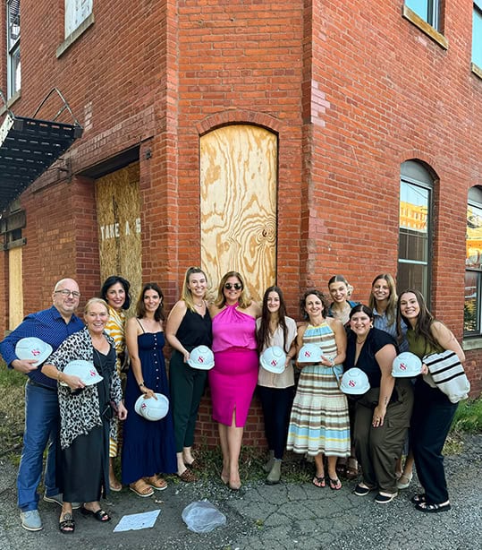 The Kate and Company team standing inside the unfinished historic building at 111 West 11th Street in Erie