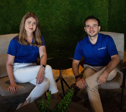 Kate Mitselmakher seated beside Sam Yilmaz, both wearing blue Bloccelerate shirts