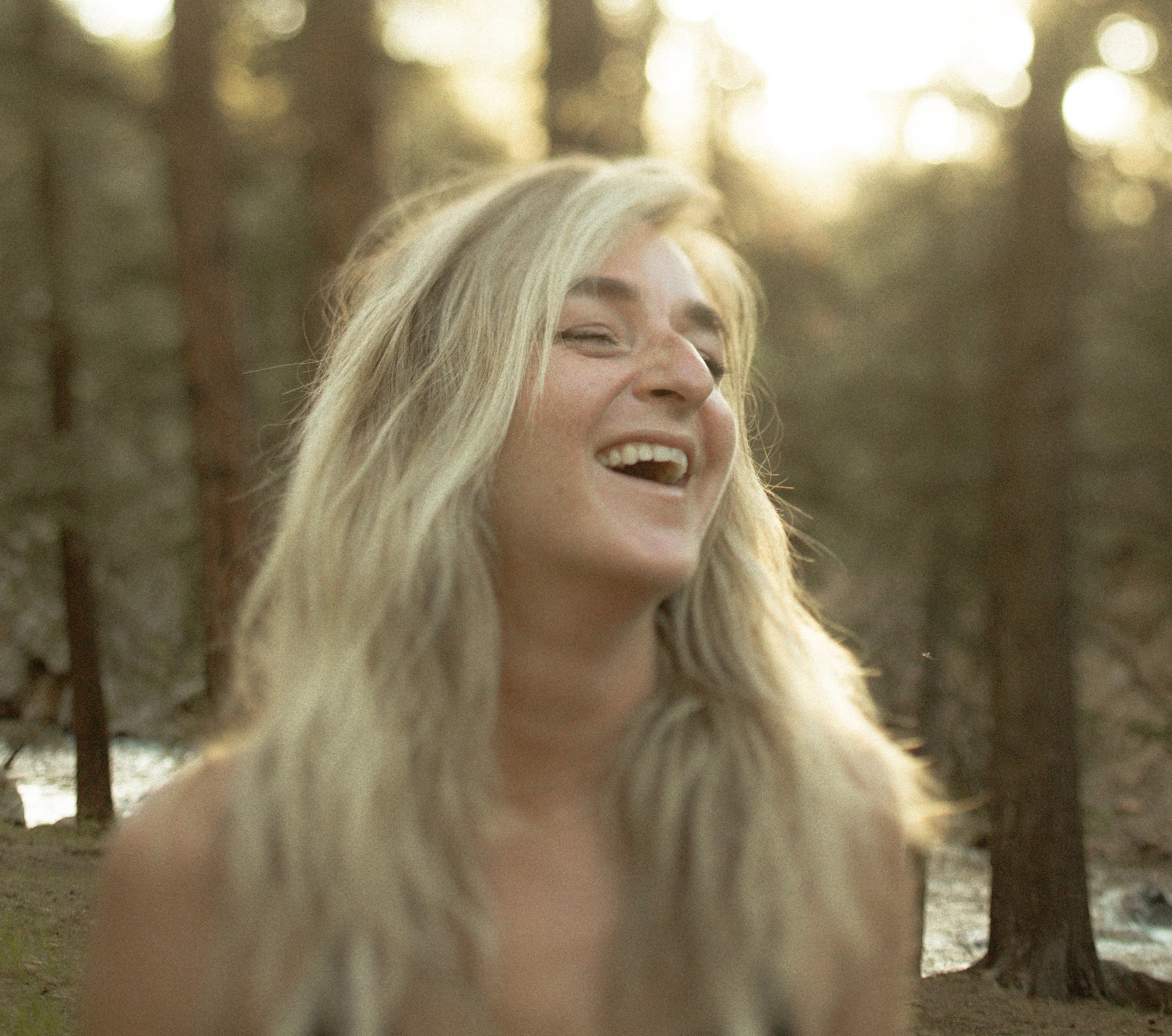 Kate Wood laughing outdoors in a wooded setting