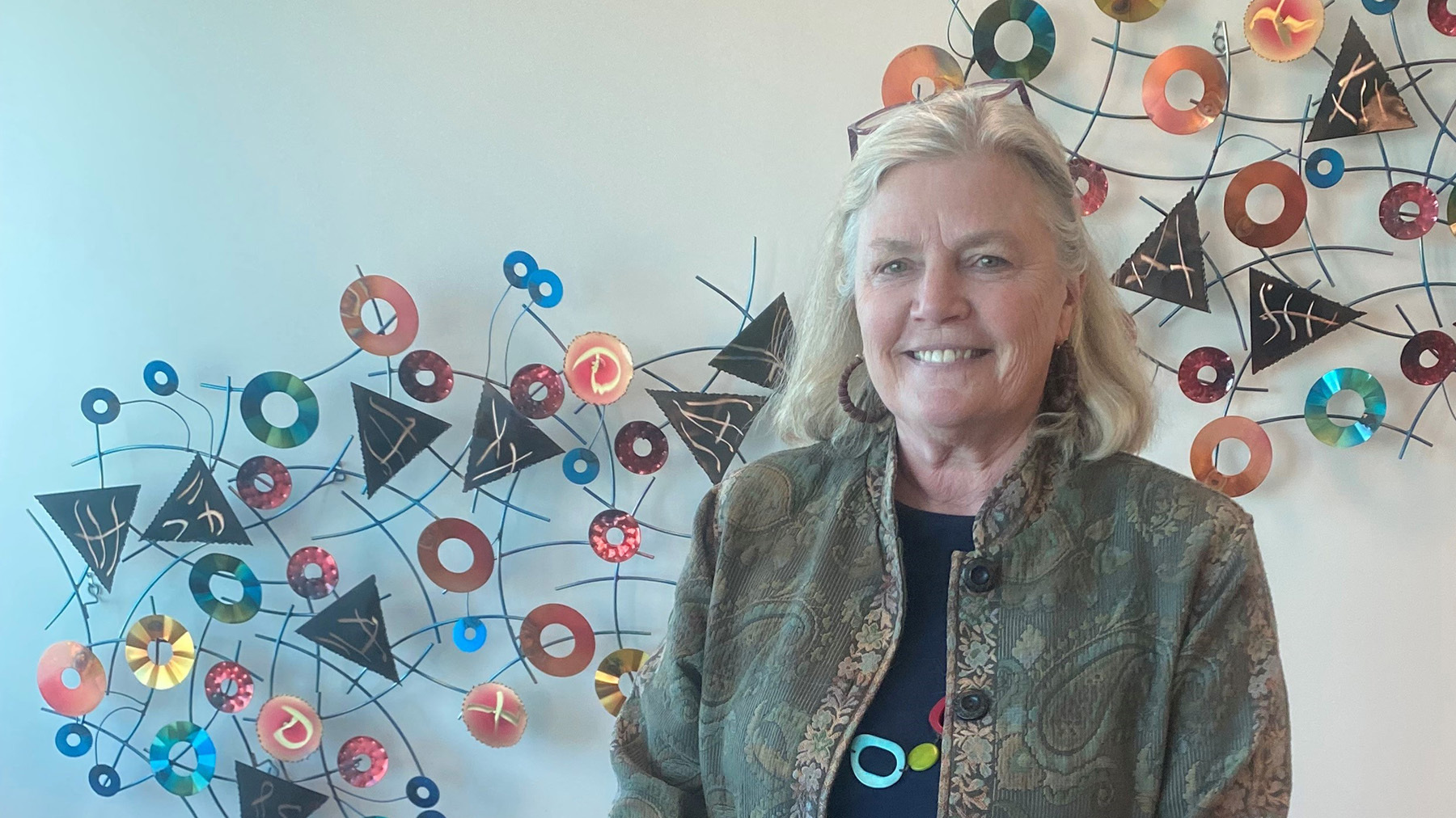 Kathy Tunheim in her office beside a colorful wall installation
