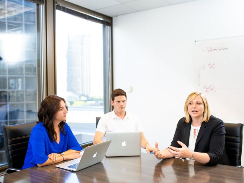 Katie Fairchild, right, speaking with two colleagues around a conference table at Hireology