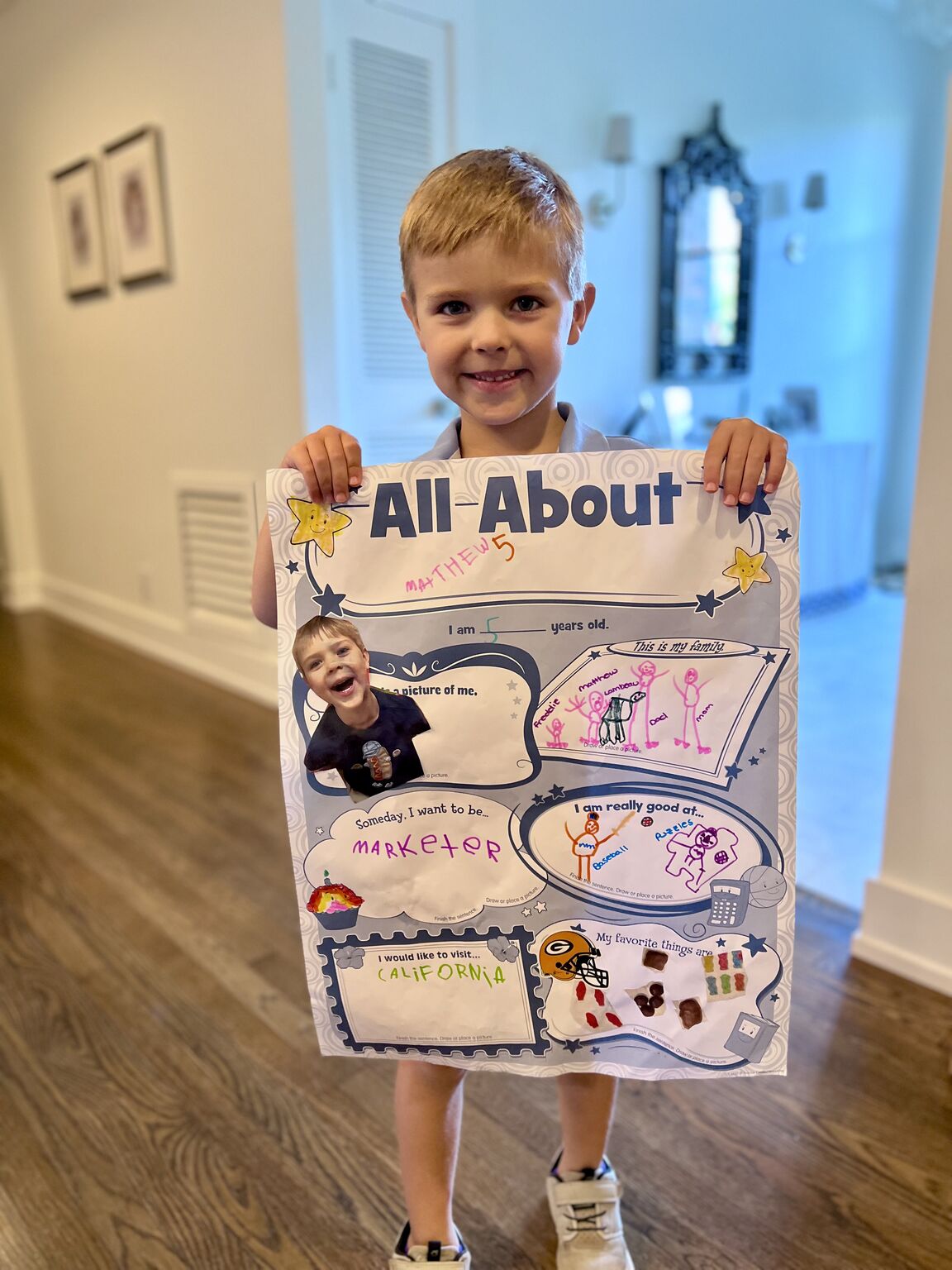 Katie Wild's son holding his All About Me school poster, which says he wants to be a marketer