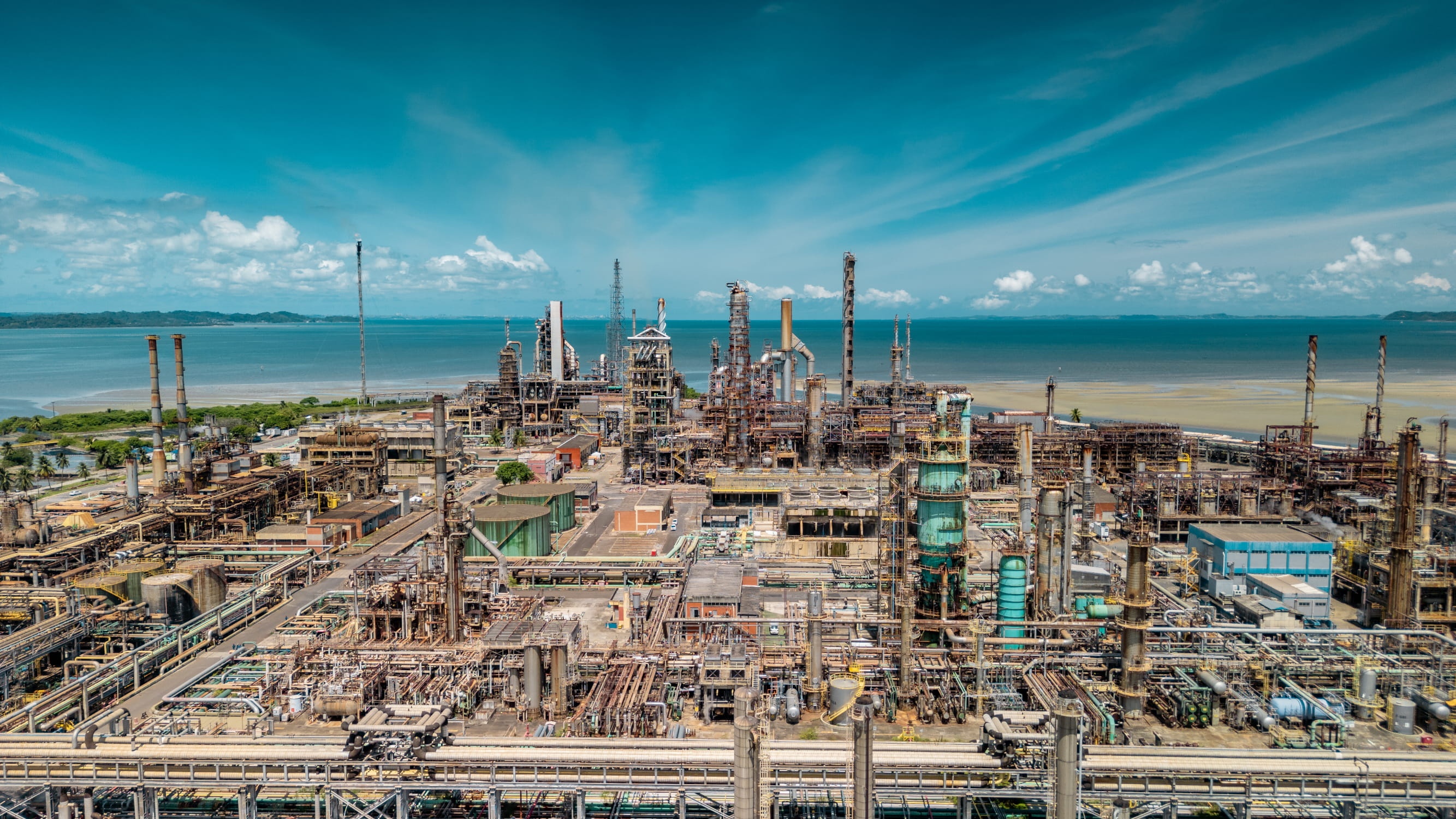 Processing towers and pipework at Acelen’s Mataripe refinery beside the water