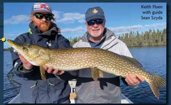 Keith Floen and guide Sean Szyda holding a northern pike beside a lake