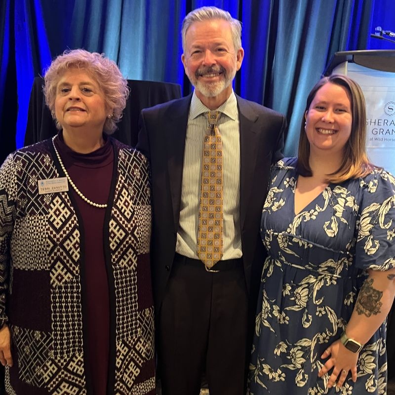 Keith Harvey, center, standing with two colleagues at the 2025 Association for Women in the Metals Industry conference.