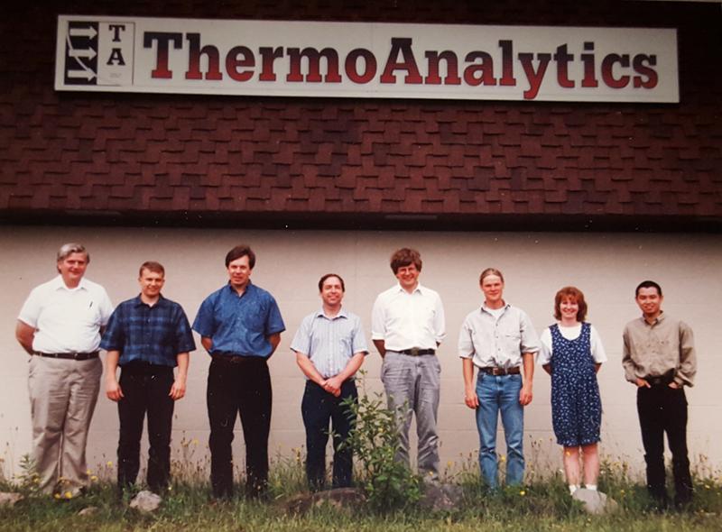 Eight members of the early ThermoAnalytics team standing below the company sign