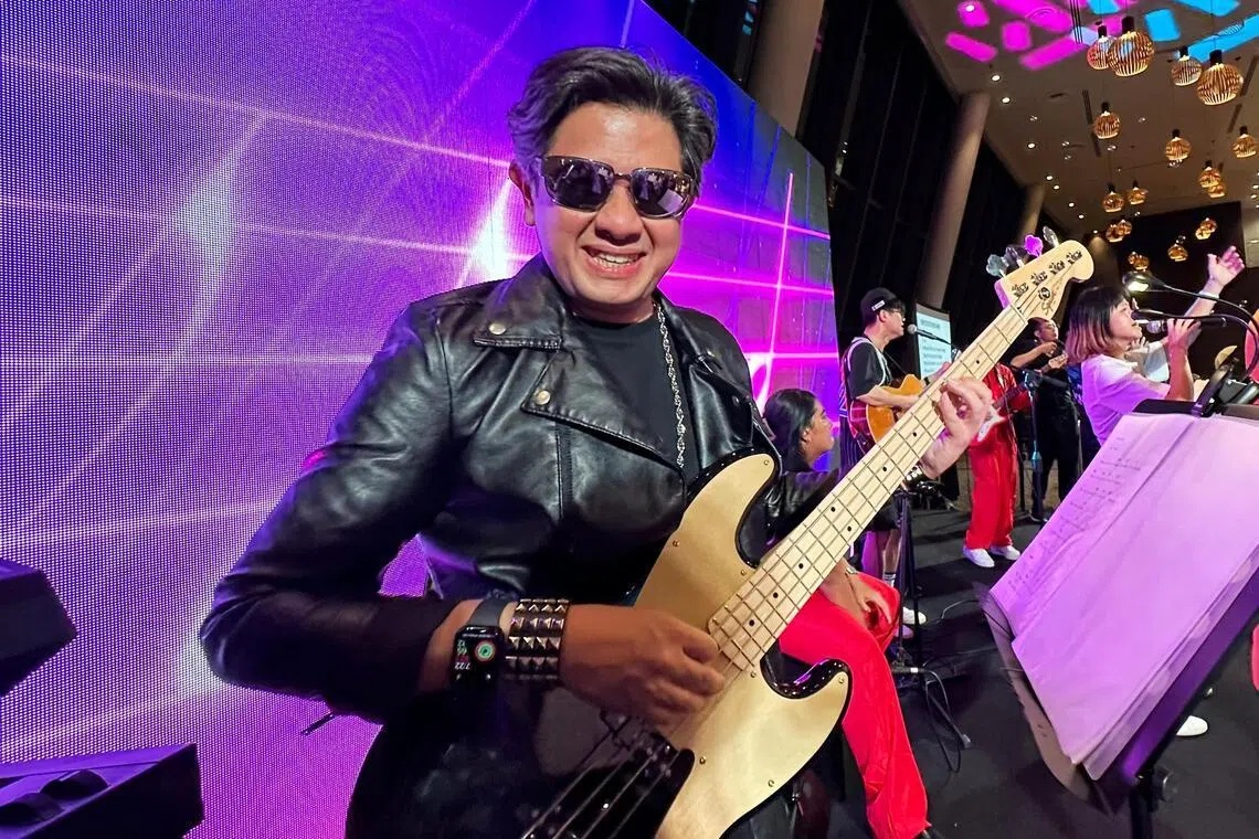 Keith Magnus smiling and playing bass guitar with the staff band Oneders at a 2023 company event
