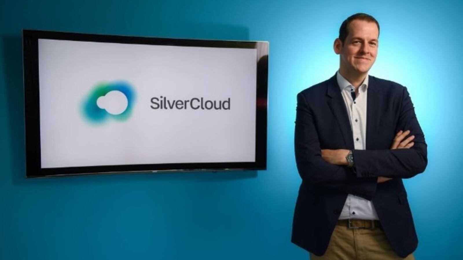 Ken Cahill standing beside a screen displaying the SilverCloud name