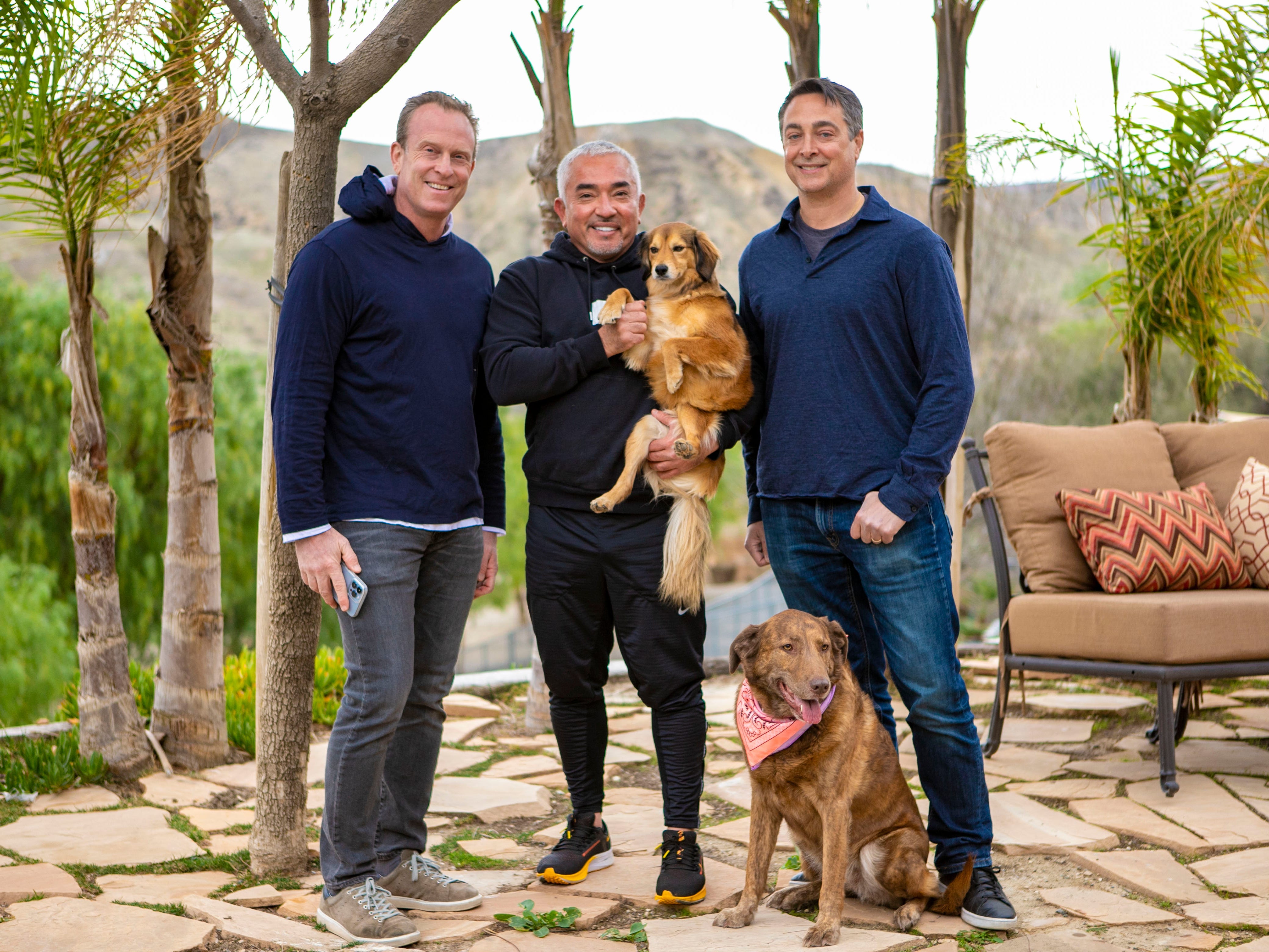 Ken Ehrman on the left with Cesar Millan, Michael Ehrman and two dogs outdoors