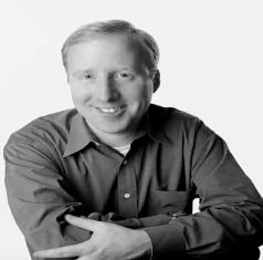 Archival black-and-white photograph of Ken Gaebler seated with his arms folded