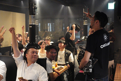 Attendees raising their hands at the EMURGO ADA payment launch in a Japanese barbecue restaurant