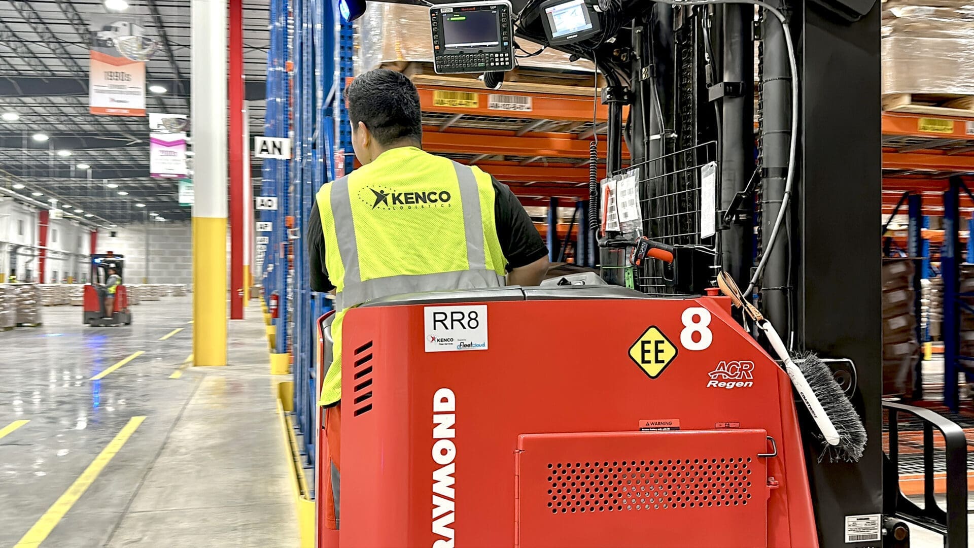 Kenco associate operating a red forklift among warehouse racks