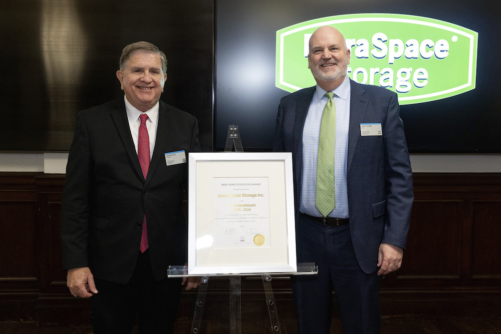 Ken Woolley, left, and Scott Stubbs beside a framed New York Stock Exchange anniversary certificate