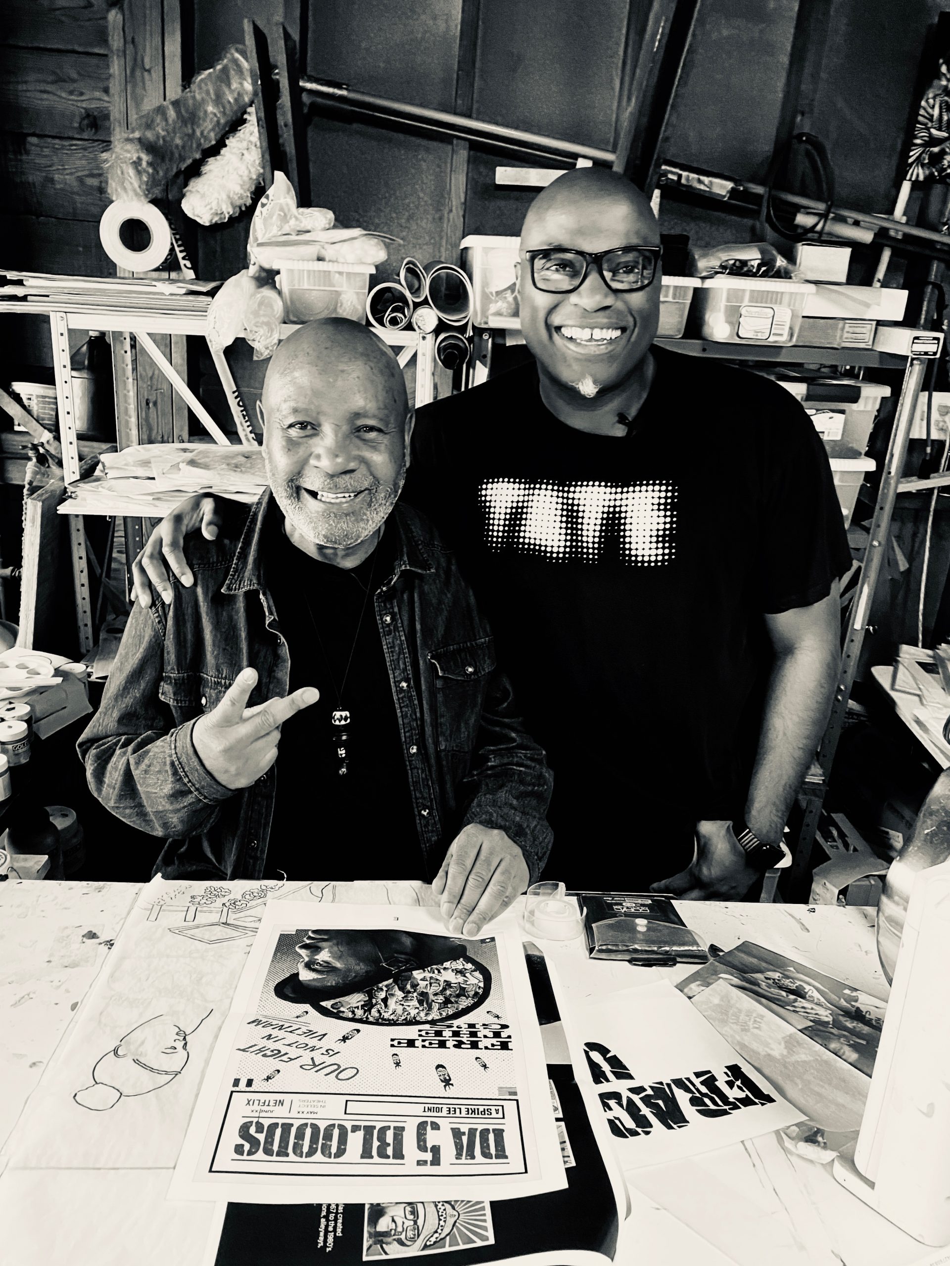 Emory Douglas, left, and Kenny Gravillis smiling together beside artwork in a studio
