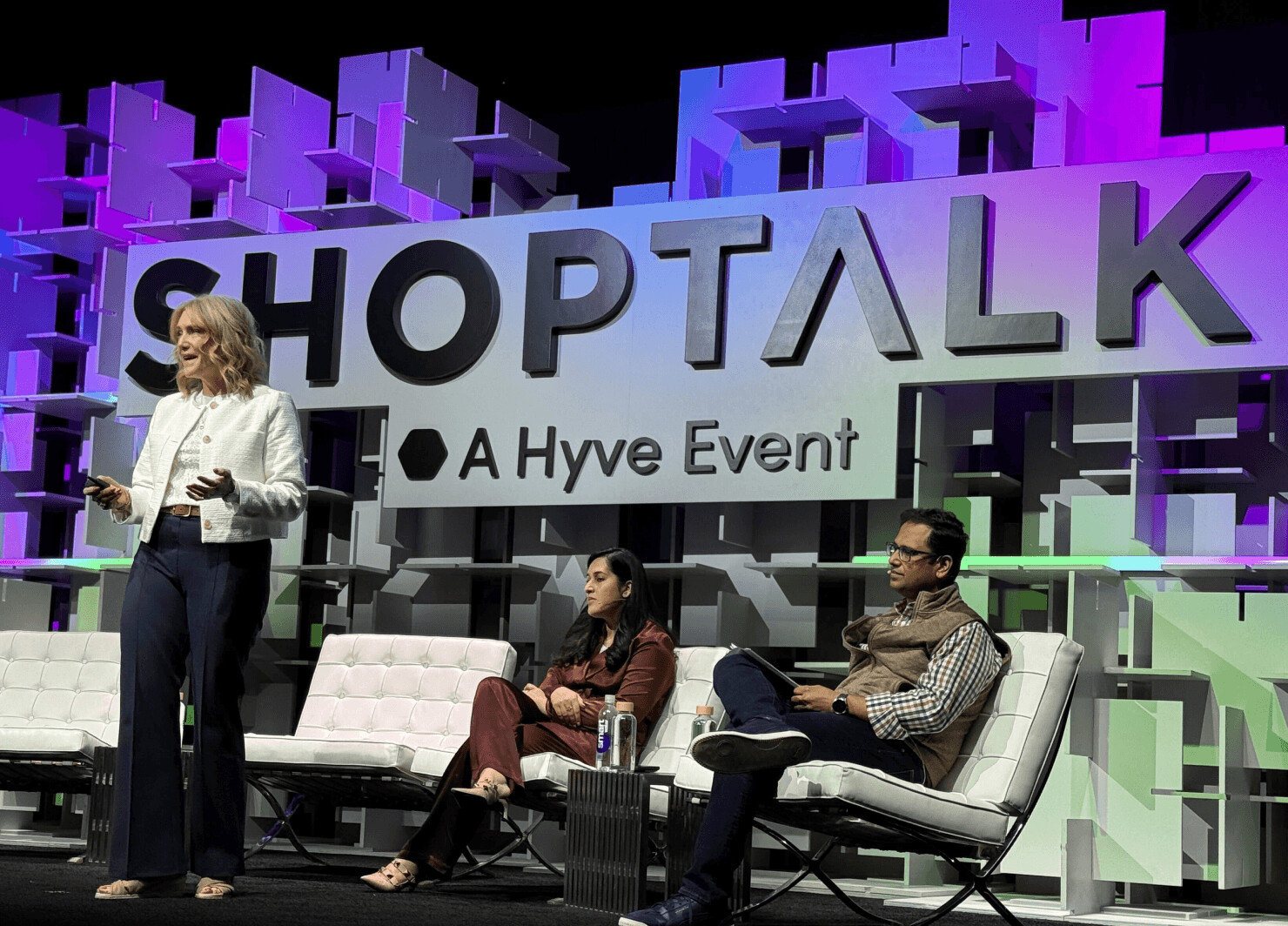 Keri McGhee speaking onstage at Shoptalk 2026 while two fellow panelists listen