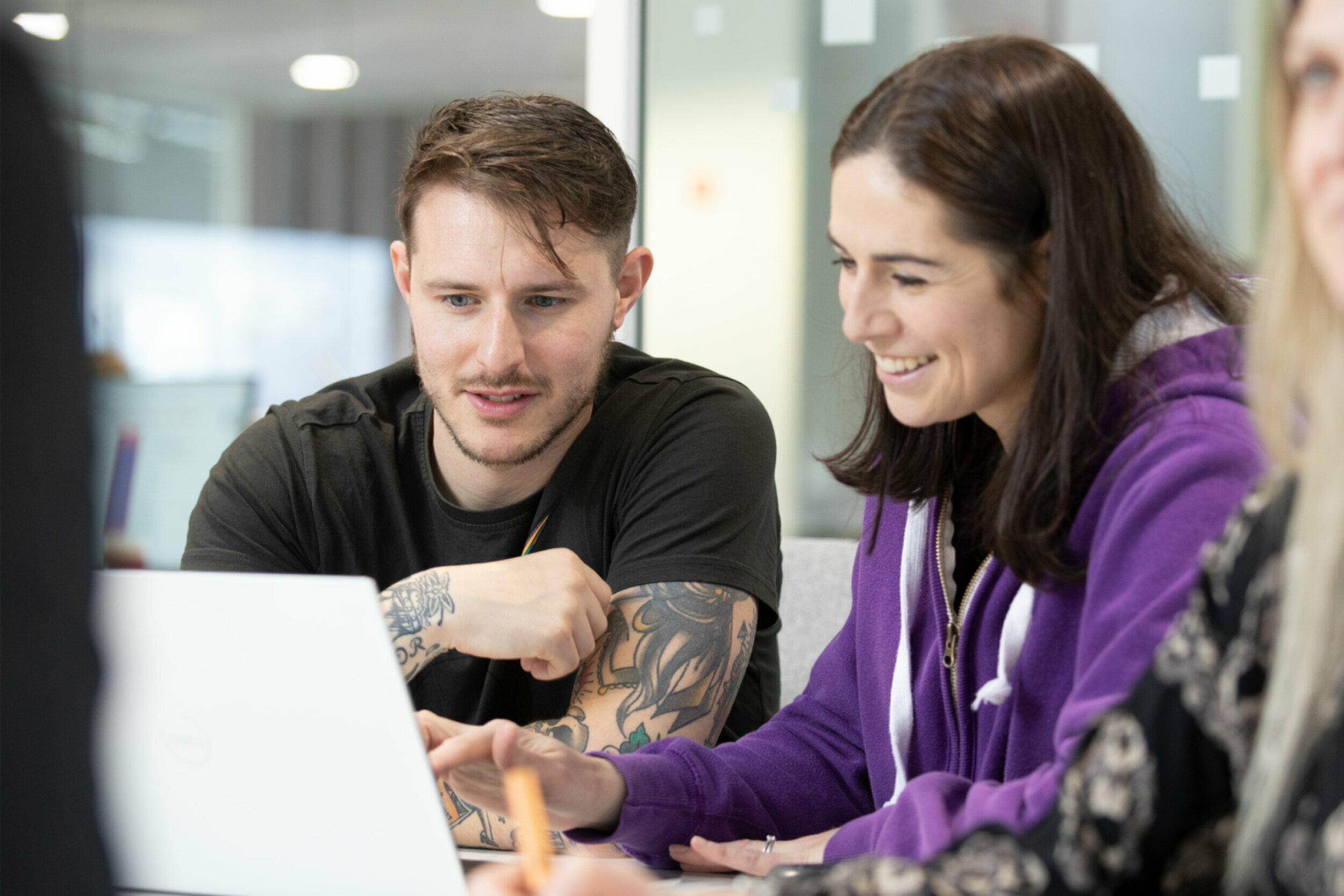 Kerv colleagues working together around a laptop in the Birmingham office