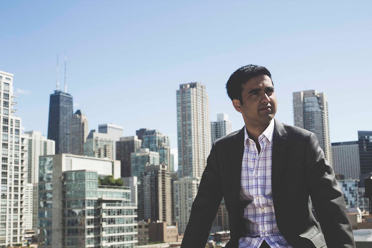 Keval Baxi standing on a Chicago rooftop with the city skyline behind him