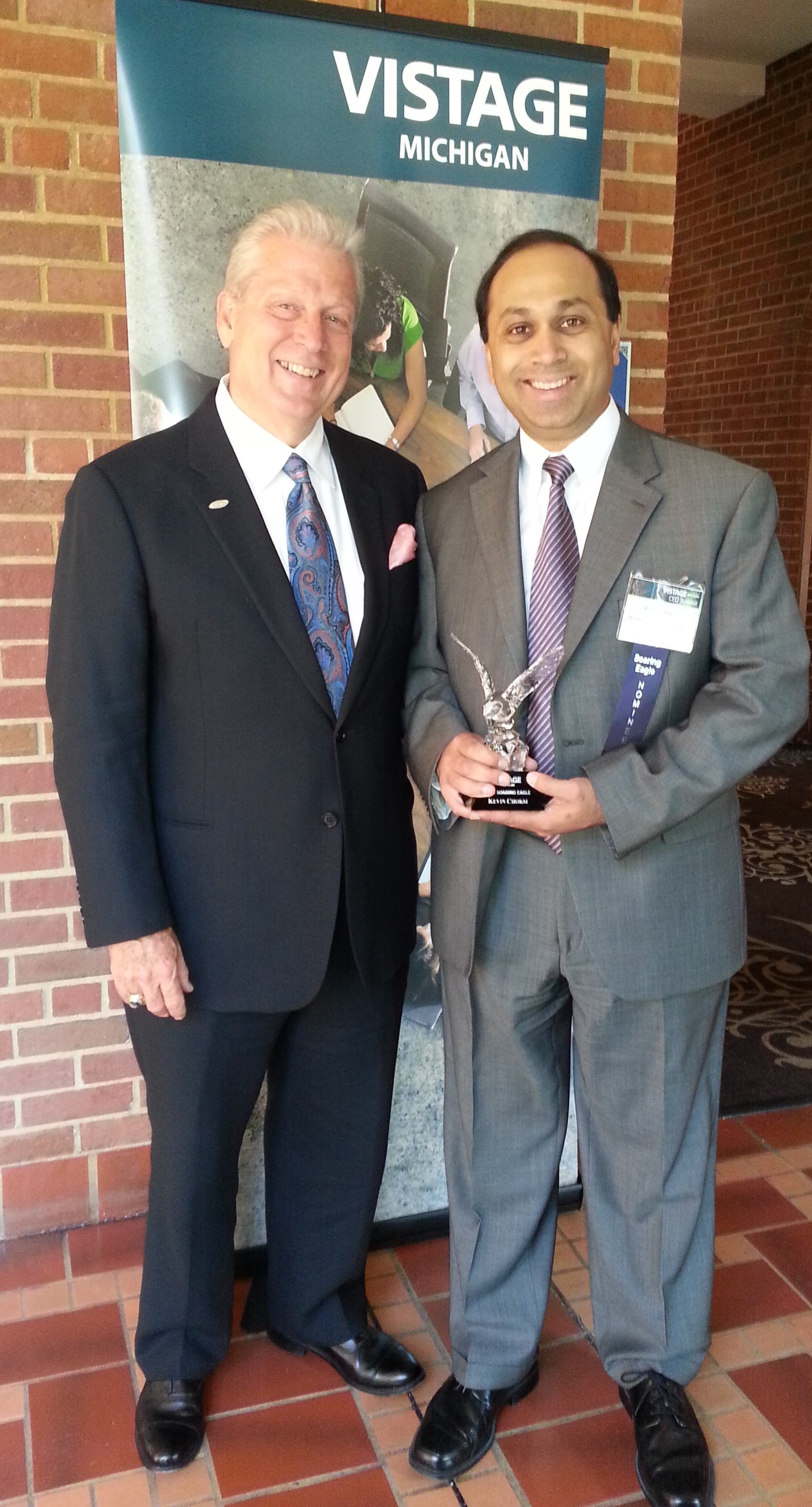 Kevin Choksi, at right, holding his Vistage Michigan Soaring Eagle Award beside another attendee