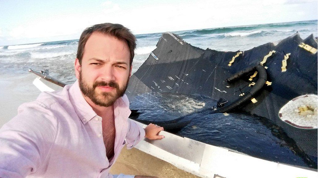 Kevin Eichelberger on a Bahamas beach beside the recovered SpaceX rocket fairing