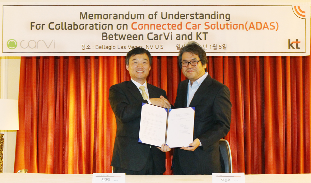 KT executive Yoon Kyung-lim, left, and CARVI CEO Kevin Lee, right, holding their signed agreement in Las Vegas in January 2016.